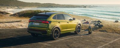 Ein Volkswagen Taigo steht an einem sonnigen Strand, präsentiert von Erich Röhr GmbH & Co. KG.