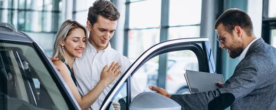 Ein Verkäufer zeigt einem lächelnden Paar ein Auto im Škoda Auto Röhr.