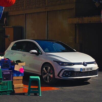 Weißer Volkswagen Golf GTE auf einem Markt mit bunten Kisten und Hockern. | © Volkswagen Zentrum Passau