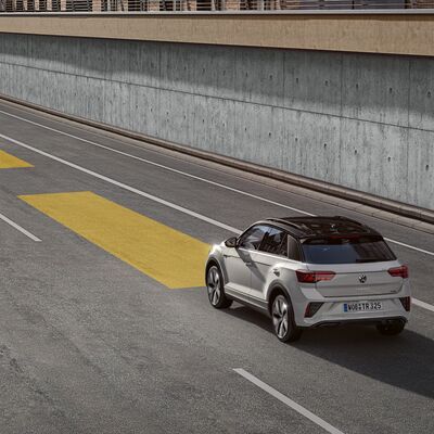 Ein weißer Volkswagen fährt auf einer Straße, die von gelben Markierungen gesäumt ist, verbunden mit Auto Röhr.