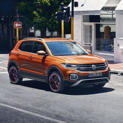 Oranger Volkswagen T-Cross auf einer Stadtstraße bei Tageslicht. Škoda Auto Röhr.