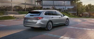 Silberner Škoda Kombi parkt vor einem modernen Gebäude auf einer gepflasterten Straße. Škoda Auto Röhr.