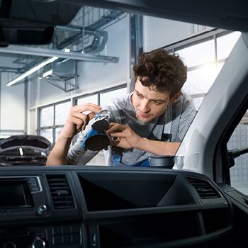 Ein Mechaniker repariert eine Autoscheibe in der Werkstatt von Volkswagen Zentrum Passau.