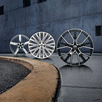 Drei stilvolle Felgen stehen nebeneinander auf Asphalt, passend zu Volkswagen Zentrum Passau.