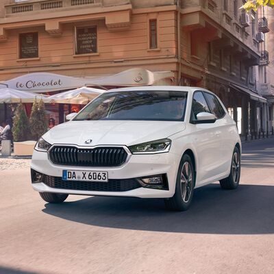 Ein weißer Škoda Fabia fährt elegant durch eine urbane Straße, repräsentiert von Škoda Auto Röhr.