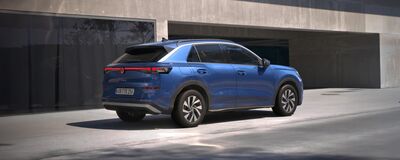 Ein blaues Auto parkt vor einem modernen Gebäude, präsentiert von Auto Röhr.