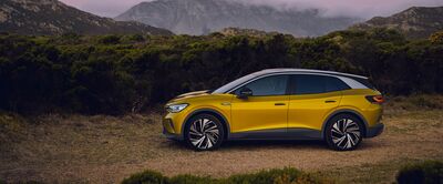 Gelber SUV auf einem Feldweg vor einer Bergkulisse bei Sonnenuntergang. Škoda Auto Röhr.