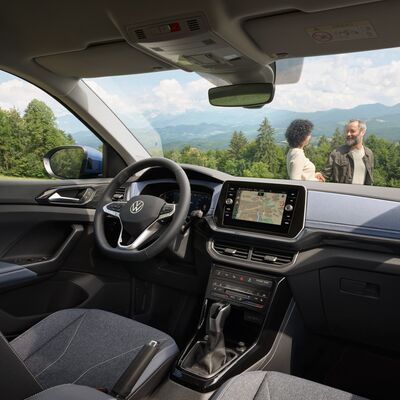 Innenansicht eines Volkswagen T-Cross mit Blick auf die Landschaft, zwei Personen im Gespräch. | Škoda Auto Röhr.
