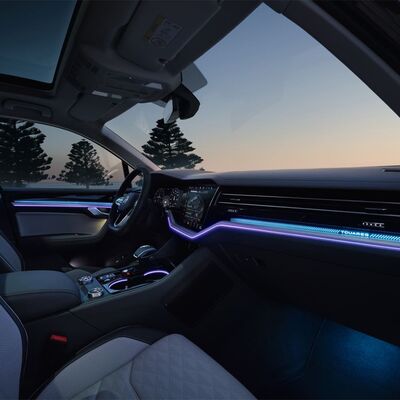 Das stilvolle Interieur eines Autos bei Sonnenuntergang zeigt eine blaue Ambientebeleuchtung, ideal für Škoda Auto Röhr.