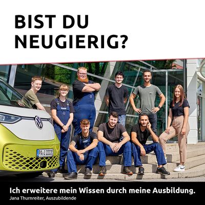 Eine Gruppe junger Auszubildender posiert fröhlich vor einem Volkswagen bei Auto Röhr.