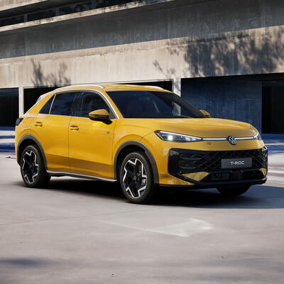 Ein gelber Volkswagen T-Roc R-Line parkt elegant vor einem modernen Gebäude, beworben von Auto Röhr.