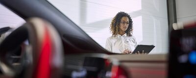 Eine Frau in einem Autohaus prüft ein Tablet neben einem Autolenkrad. | Škoda Auto Röhr.
