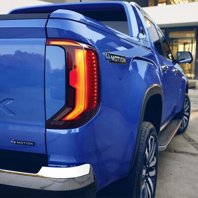 Blauer Pickup mit 4MOTION-Emblem, aufgenommen bei Auto Röhr. Das Fahrzeug steht vor einem modernen Gebäude.