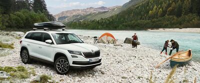 Weißer Škoda Kodiaq parkt an einem Flussufer mit Zelt und Familie. Ideal für Abenteuer. Škoda Auto Röhr.