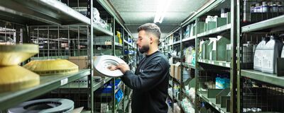 Ein Mitarbeiter sortiert Autoteile in einem Lager von Auto Röhr, um die Übersicht über Ersatzteile zu gewährleisten.