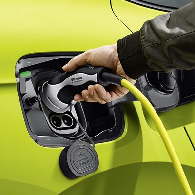 Hand lädt grünes Enyaq Coupé RS iV mit Ladekabel. Škoda Auto Röhr.