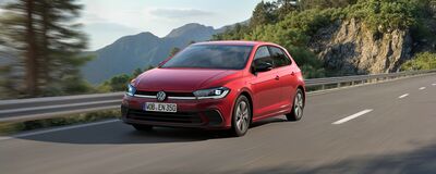 Ein roter Volkswagen fährt dynamisch auf einer kurvenreichen Bergstraße, inspiriert von Auto Röhr.