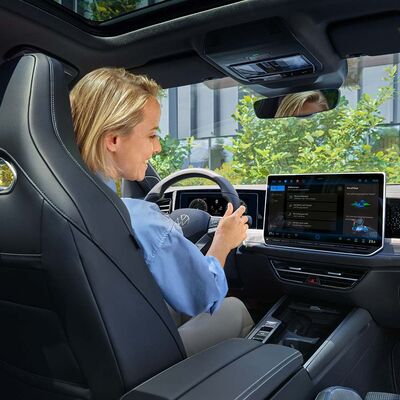Frau fährt neuen VW Passat mit modernem Display, gezeigt im Volkswagen Zentrum Passau.