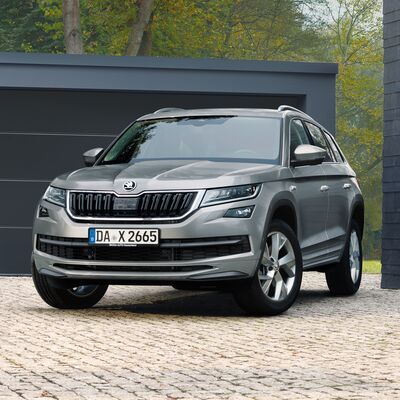 Silberner Škoda Kodiaq SUV parkt vor einer modernen Garage, umgeben von Bäumen. Škoda Auto Röhr.