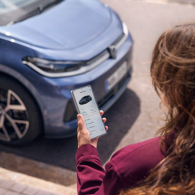 Eine Person nutzt ihr Smartphone, um Informationen zu ihrem Volkswagen ID.3 Neo von Auto Röhr abzurufen.