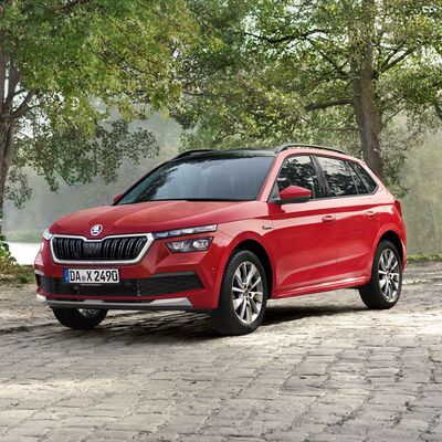 Roter Škoda Kamiq auf gepflastertem Weg vor grüner Waldkulisse. Škoda Auto Röhr.