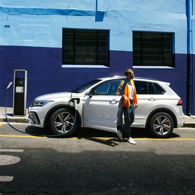 Ein Mann steigt aus einem weißen Auto an einer Ladestation aus. | Škoda Auto Röhr.