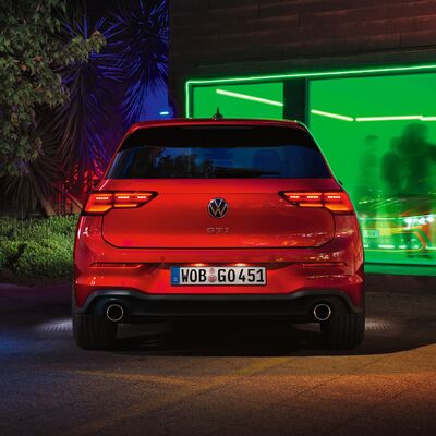 Roter Volkswagen Golf GTI bei Nacht vor einem beleuchteten Gebäude. Škoda Auto Röhr.
