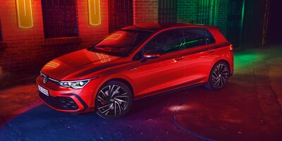 Roter Volkswagen Golf GTI in bunter Beleuchtung, geparkt vor Backsteinwand. | © Volkswagen Zentrum Passau