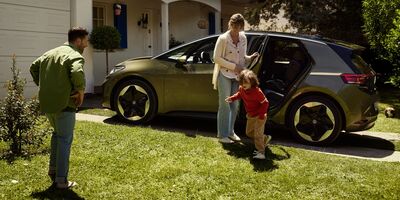 Eine Familie steigt aus einem modernen Volkswagen vor einem Haus aus. Ein Kind läuft auf einen Mann zu. Volkswagen Zentrum Passau.