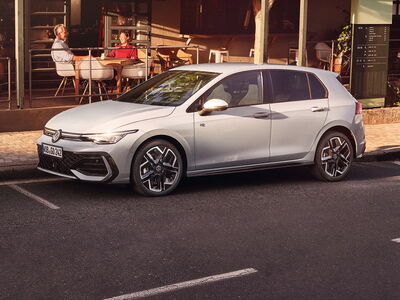 Ein stilvoller Volkswagen Golf parkt an der Straße vor einem Café, wo Gäste entspannt sitzen. | © Erich Röhr GmbH & Co. KG