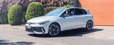 Ein weißer Volkswagen R-Line parkt vor einer Hecke, bereit für die Fahrt vom Volkswagen Zentrum Passau.