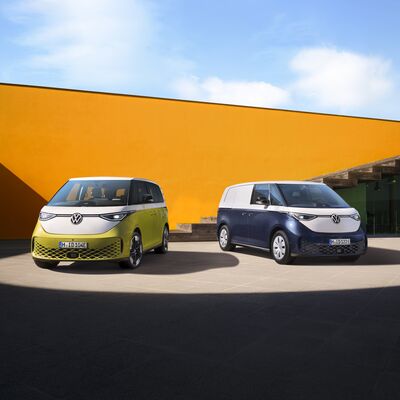 Zwei moderne Volkswagen ID.Buzz vor einer gelben Wand bei Auto Röhr.