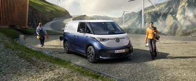 Ein blauer Volkswagen ID. Buzz parkt in einer bergigen Landschaft. Zwei Personen mit Ausrüstung stehen daneben. Volkswagen Zentrum Passau.