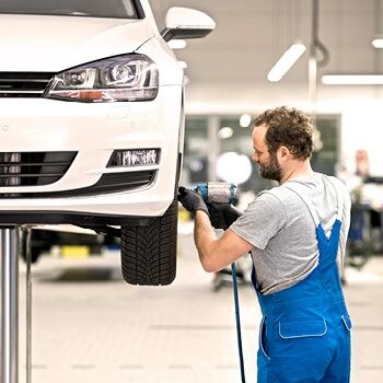 Ein Mechaniker wechselt die Räder eines weißen Autos beim Volkswagen Zentrum Passau.
