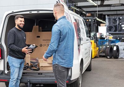 Zwei Männer laden LKW-Teile in einen Transporter bei Auto Röhr ein, um NORA-Retouren zu bearbeiten.