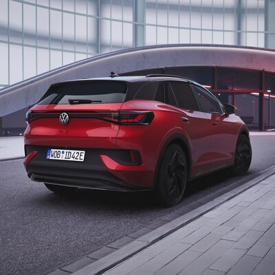 Ein roter Volkswagen ID.4 GTX steht modern beleuchtet vor einer futuristischen Architektur, ideal für Auto Röhr.