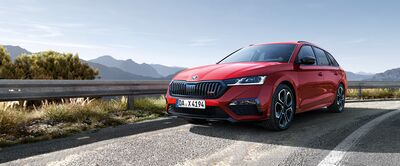 Roter Škoda Octavia RS auf einer kurvigen Landstraße vor malerischer Bergkulisse. Škoda Auto Röhr.