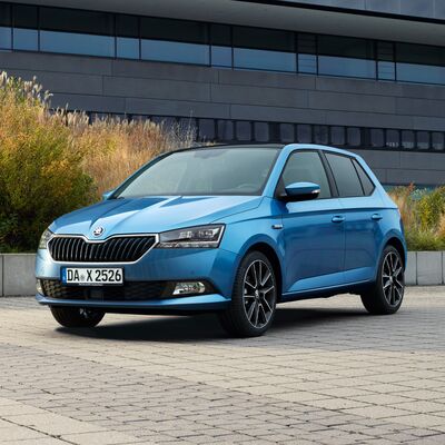 Blauer Škoda Fabia auf gepflastertem Parkplatz vor modernem Gebäude. Škoda Auto Röhr.