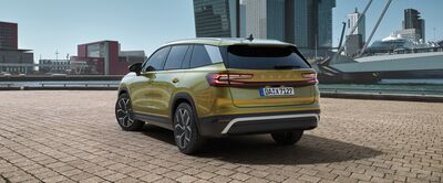 Gelber Škoda SUV auf gepflastertem Platz vor moderner Stadtlandschaft. Škoda Auto Röhr.