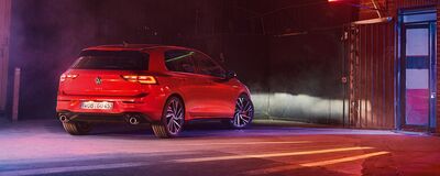 Roter Volkswagen Golf GTI in einer stimmungsvoll beleuchteten Garage bei Nacht. | Škoda Auto Röhr