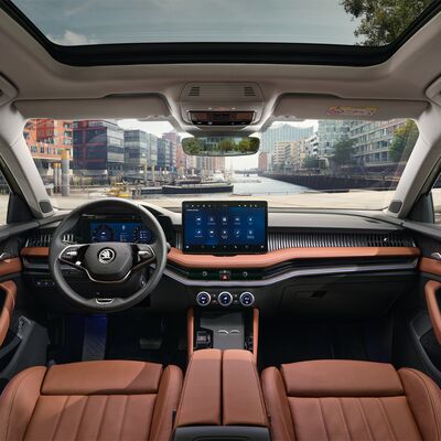 Innenansicht eines Škoda mit modernem Armaturenbrett und Panoramadach, geparkt am Wasser. Škoda Auto Röhr.