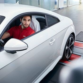 Ein Mann im roten Shirt sitzt in einem weißen Audi bei der Wartung im Volkswagen Zentrum Passau.