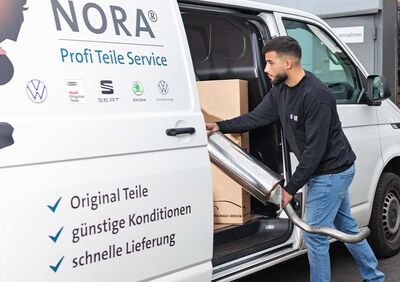 Ein Mann lädt einen Auspuff in einen NORA-Transporter, der für Škoda Auto Röhr Ersatzteile liefert.