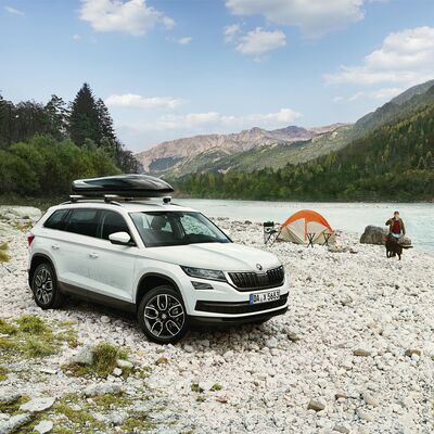 Ein weißer Škoda SUV mit Dachträger steht auf einem Kiesstrand neben einem Zelt. | © Škoda Auto Röhr