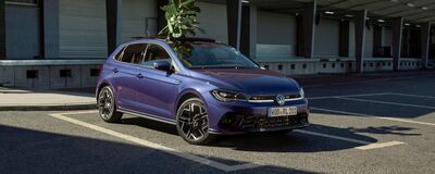 Ein blauer Volkswagen Polo steht im Sonnenlicht geparkt vor dem Volkswagen Zentrum Passau.