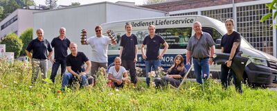Eine Gruppe von Mitarbeitern von Auto Röhr posiert vor einem Lieferwagen im Freien.