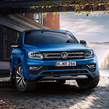 Blauer Volkswagen Amarok Aventura parkt auf einer gepflasterten Straße vor einem Gebäude. Keywords: Volkswagen Zentrum Passau.