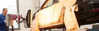 Ein Techniker im Volkswagen Zentrum Passau arbeitet an der Lackierung eines Autos in einer spezialisierten Werkstatt.