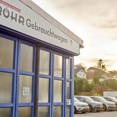 Eine Reihe von Autos bei Auto Röhr Gebrauchtwagen, mit der Abendsonne im Hintergrund.