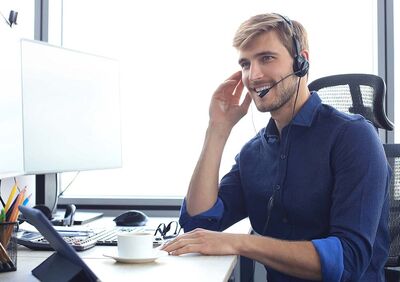 Ein lächelnder Mann mit Headset bietet am Schreibtisch Support für Auto Röhr an.